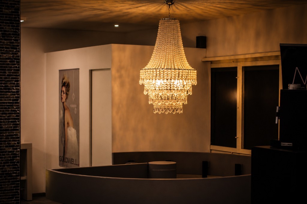 Kristallkronleuchter, warme Beleuchtung und Goldwell-Wandbild im Salon