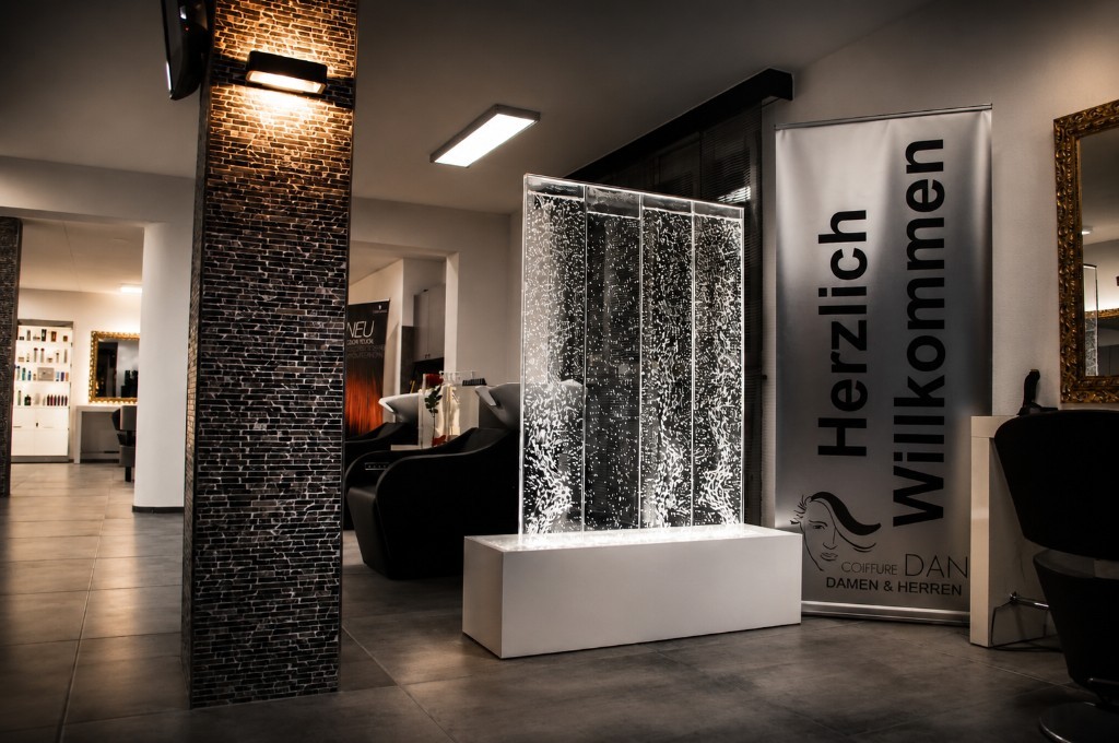 Innenraum mit beleuchteter Wasserblasenwand und Herzlich-Willkommen-Banner